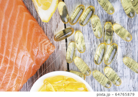 Handful of omega 3 softgels and salmon filet 64765879