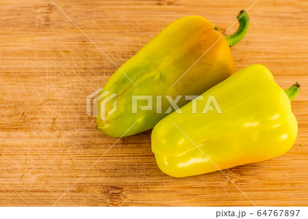 pair of yellow green sweet peppers pods lie on a pair of yellow green sweet peppers pods lie on a 64767897