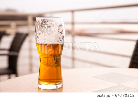 base a glass of cold beer stands on the table of a 64770218