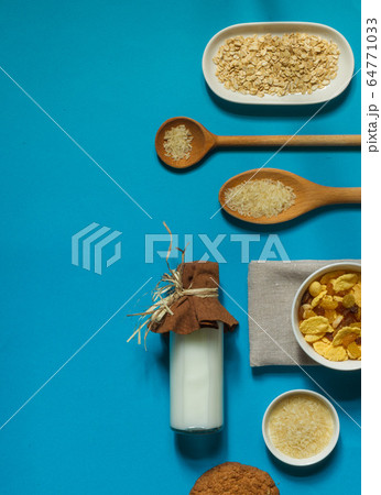 flatlay with a bottle of rice milk, corn flakes and dried fruit on a bright blue background with space, vertical flatlay with a bottle of rice milk, corn flakes and dried fruit on a bright blue background with space, vertical 64771033