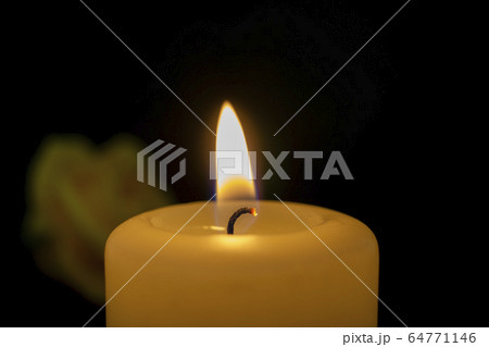 Close up of burning yellow wax candle and rose 64771146