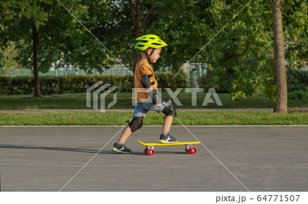 A little boy enjoys a yellow cruiser penny A little boy enjoys a yellow cruiser penny 64771507