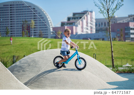 A little boy enjoys a balance bike 64771587