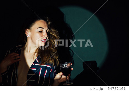 girl on green background with a glass of red drink wine smoke looks aside girl on green background with a glass of red drink wine smoke looks aside 64772161