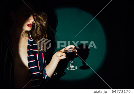 girl on green background with a glass of red drink wine smoke looks aside 64772170