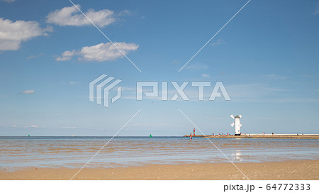 lighthouse and windmill on the seashore 64772333