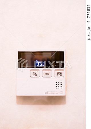 白壁に設置された家庭用の給湯器のリモコン 64775636