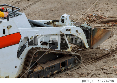 Mini bulldozer with earth doing landscaping works 64776740