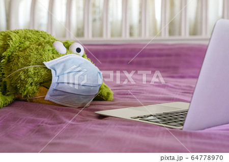 Green soft toy wearing medical face mask and 64778970