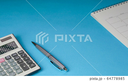 Calculator, pen and table calendar on blue 64778985