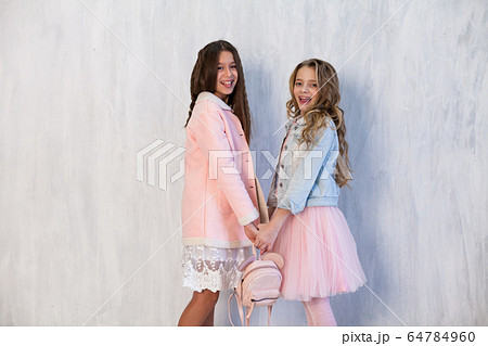 Two beautiful fashionable girl girlfriends in white pink dresses Two beautiful fashionable girl girlfriends in white pink dresses 64784960