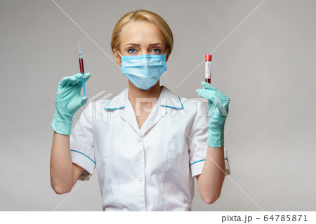 medical doctor nurse woman wearing protective mask and gloves - holding virus blood test and syringe medical doctor nurse woman wearing protective mask and gloves - holding virus blood test and syringe 64785871