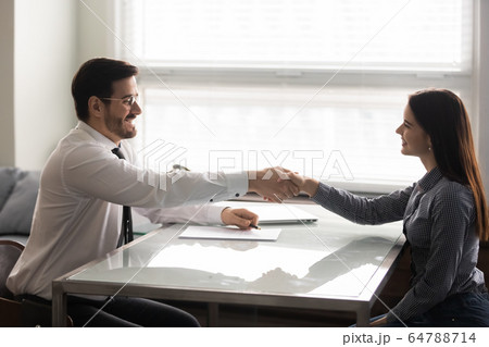 Smiling woman candidate shaking hands with businessman at job interview. Smiling woman candidate shaking hands with businessman at job interview. 64788714