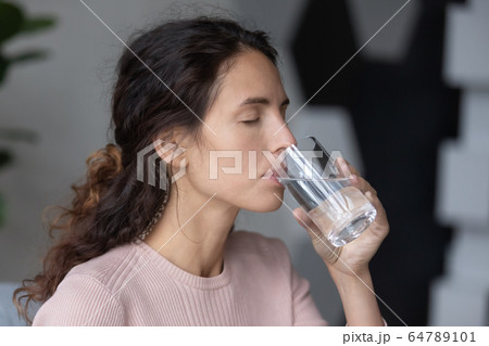 Peaceful calm millennial woman drinking glass of pure distilled aqua. Peaceful calm millennial woman drinking glass of pure distilled aqua. 64789101