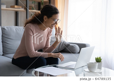 Happy young attractive woman holding video call with friends. 64789135