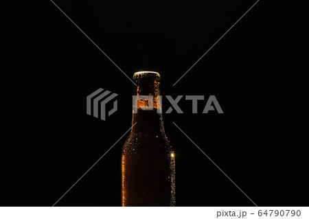 Bottle of beer with drops of water close-up on a black isolated background. 64790790