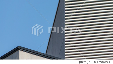 striped wall of a gray tall building against a blue sky 64790893