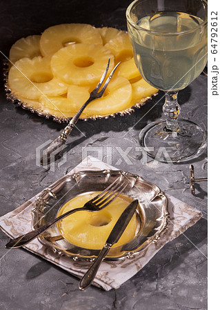 Canned pineapple, cut into rings on a metal plate 64792612