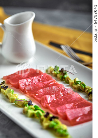 Slices of raw tuna sashimi served on white board with avocado Slices of raw tuna sashimi served on white board with avocado 64793041