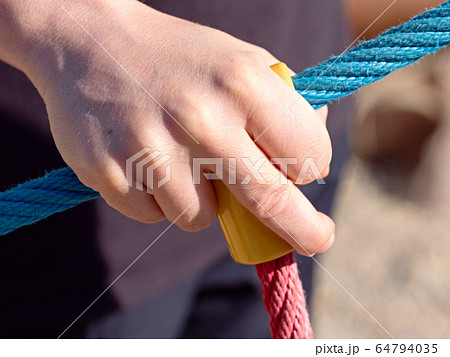 Hand holding rope while climbing a wooden wall. Hand holding rope while climbing a wooden wall. 64794035