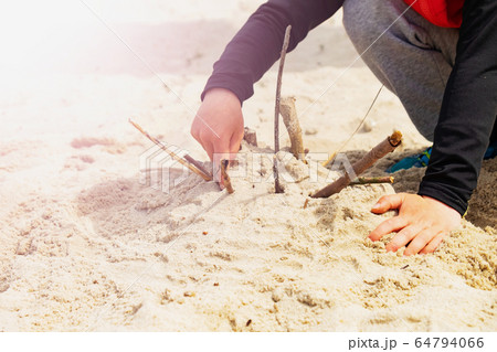 Boys hands playing in the sand at the beach. 64794066
