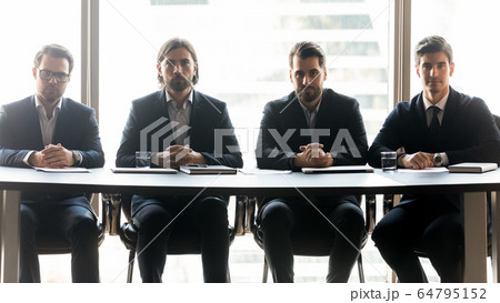 Four serious businessmen sitting in row at meeting 64795152