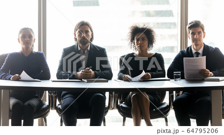 Four confident diverse hr managers sitting at table in row Four confident diverse hr managers sitting at table in row 64795206