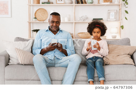 Gadget overuse problem. Senior African American man and granddaughter with smartphones at home 64797306