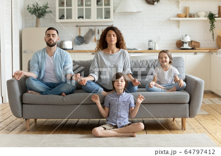 Peaceful calm couple practicing yoga exercises with small children. Peaceful calm couple practicing yoga exercises with small children. 64797412
