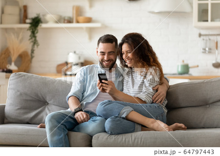 Happy young wife showing funny video to laughing husband. 64797443