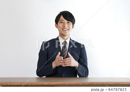 相手に向かって話をするスーツ姿の若い男性　 64797825
