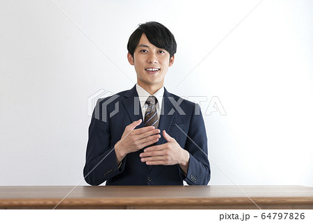 相手に向かって話をするスーツ姿の若い男性　 64797826
