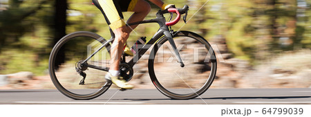Professional male cyclist in racing outfit during a ride on bike outdoors. Panning technique used 64799039