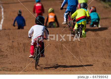 BMX riders competing in the child class on the off-road circuit 64799042
