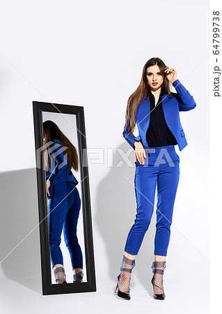 Beautiful girl in pantsuit and tulle socks near the mirror touching hair Beautiful girl in pantsuit and tulle socks near the mirror touching hair 64799738