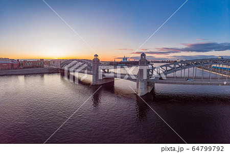 St. Petersburg Russia. Aerial panoramic view from drone to Peter the Great bridge of white nights. Bolsheokhtinsky bridge across the river Neva with evening lighting city with driving cars on highway. St. Petersburg Russia. Aerial panoramic view from drone to Peter the Great bridge of white nights. Bolsheokhtinsky bridge across the river Neva with evening lighting city with driving cars on highway. 64799792