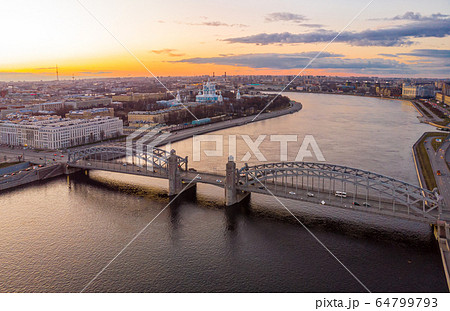St. Petersburg Russia. Aerial panoramic view from drone to Peter the Great bridge of white nights. Bolsheokhtinsky bridge across the river Neva with evening lighting city with driving cars on highway. St. Petersburg Russia. Aerial panoramic view from drone to Peter the Great bridge of white nights. Bolsheokhtinsky bridge across the river Neva with evening lighting city with driving cars on highway. 64799793