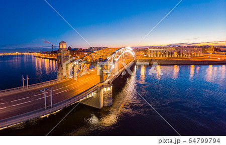 St. Petersburg Russia. Aerial panoramic view from drone to Peter the Great bridge of white nights. Bolsheokhtinsky bridge across the river Neva with evening lighting city with driving cars on highway. 64799794