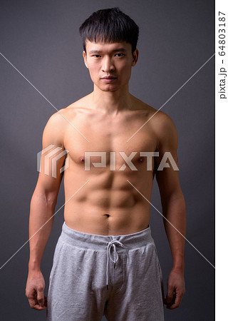 Young shirtless Chinese man against gray background Young shirtless Chinese man against gray background 64803187