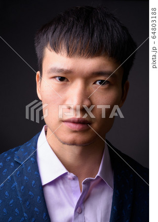 Portrait of young Chinese businessman against gray background 64803188