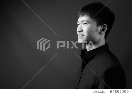 Studio shot of young Chinese man in black and white Studio shot of young Chinese man in black and white 64803309
