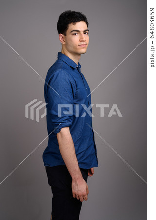 Portrait of young handsome businessman against gray background Portrait of young handsome businessman against gray background 64803659