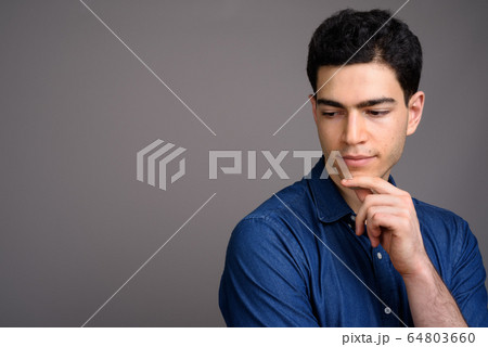 Portrait of young handsome businessman against gray background Portrait of young handsome businessman against gray background 64803660