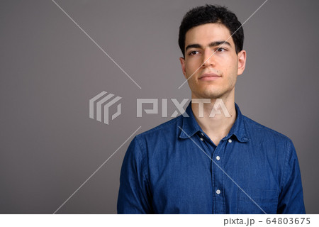 Portrait of young handsome businessman against gray background Portrait of young handsome businessman against gray background 64803675