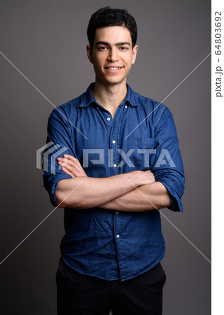 Portrait of young handsome businessman against gray background Portrait of young handsome businessman against gray background 64803692