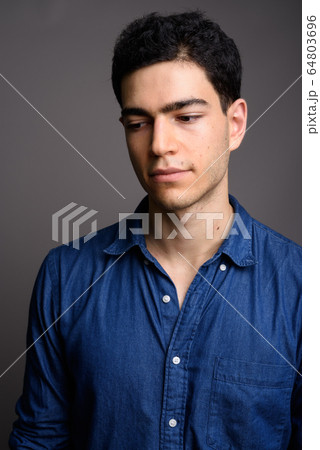 Portrait of young handsome businessman against gray background Portrait of young handsome businessman against gray background 64803696