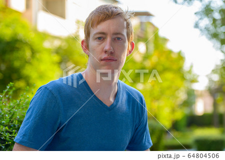 Portrait of man with red hair relaxing in the park Portrait of man with red hair relaxing in the park 64804506