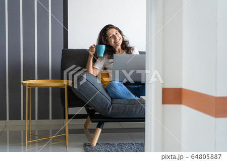 Beautiful girl sitting with a laptop on a sofa in 64805887