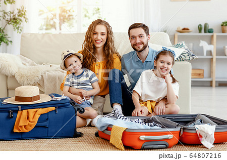 Cheerful family with suitcases on floor looking at 64807216