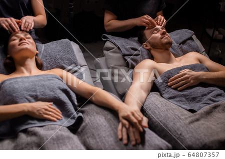 charming married couple enjoying head massage in modern wellness salon charming married couple enjoying head massage in modern wellness salon 64807357